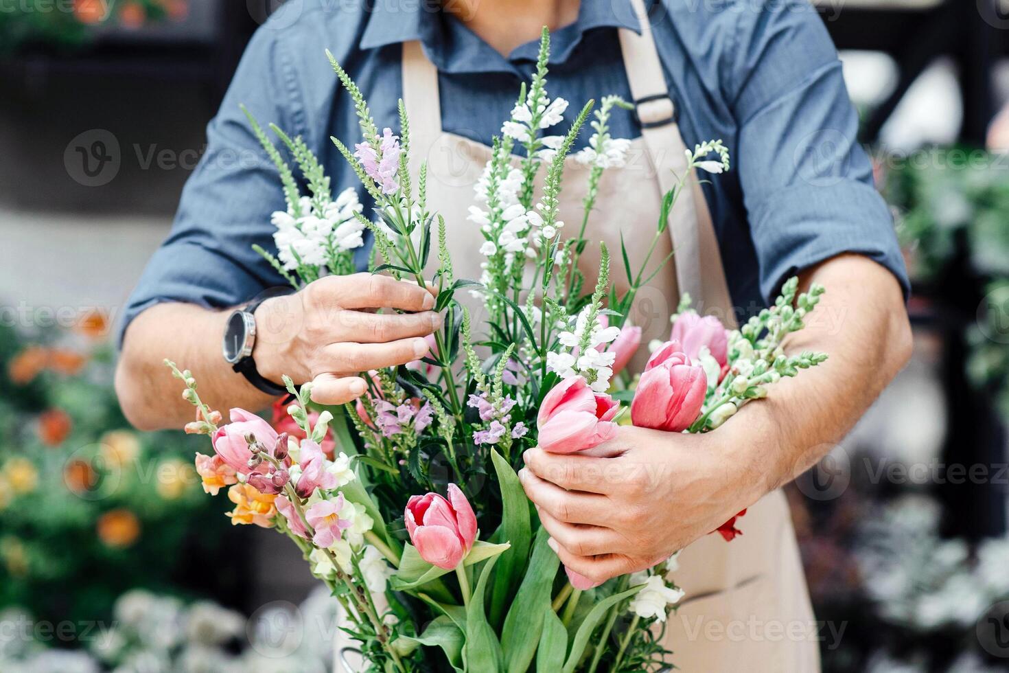 Florist making fresh flowers bouquet composition. Millennial small business owner, designer man in protective mask and apron work for client during social distancing in plant studio, copy space photo