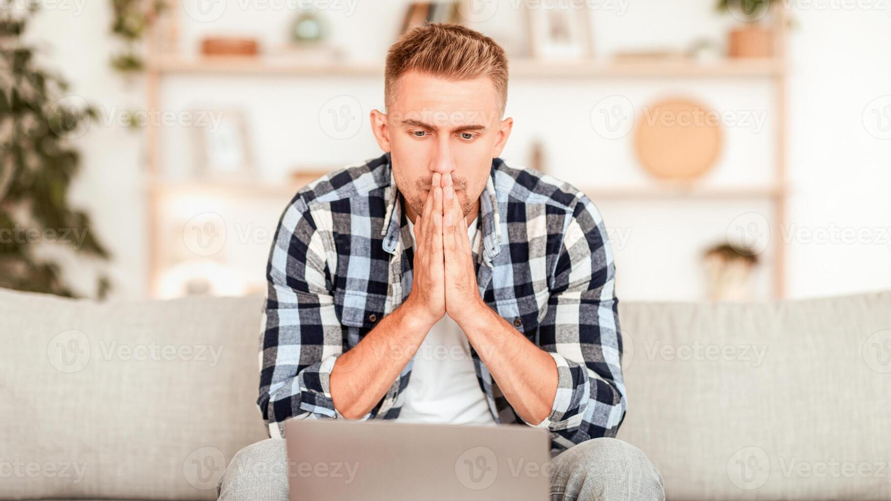 Making Decision Concept. Stressed casual guy looking at laptop screen sitting on sofa in living room. Contemplating man thinking, having problems, copy space. Sad focused male working at computer photo