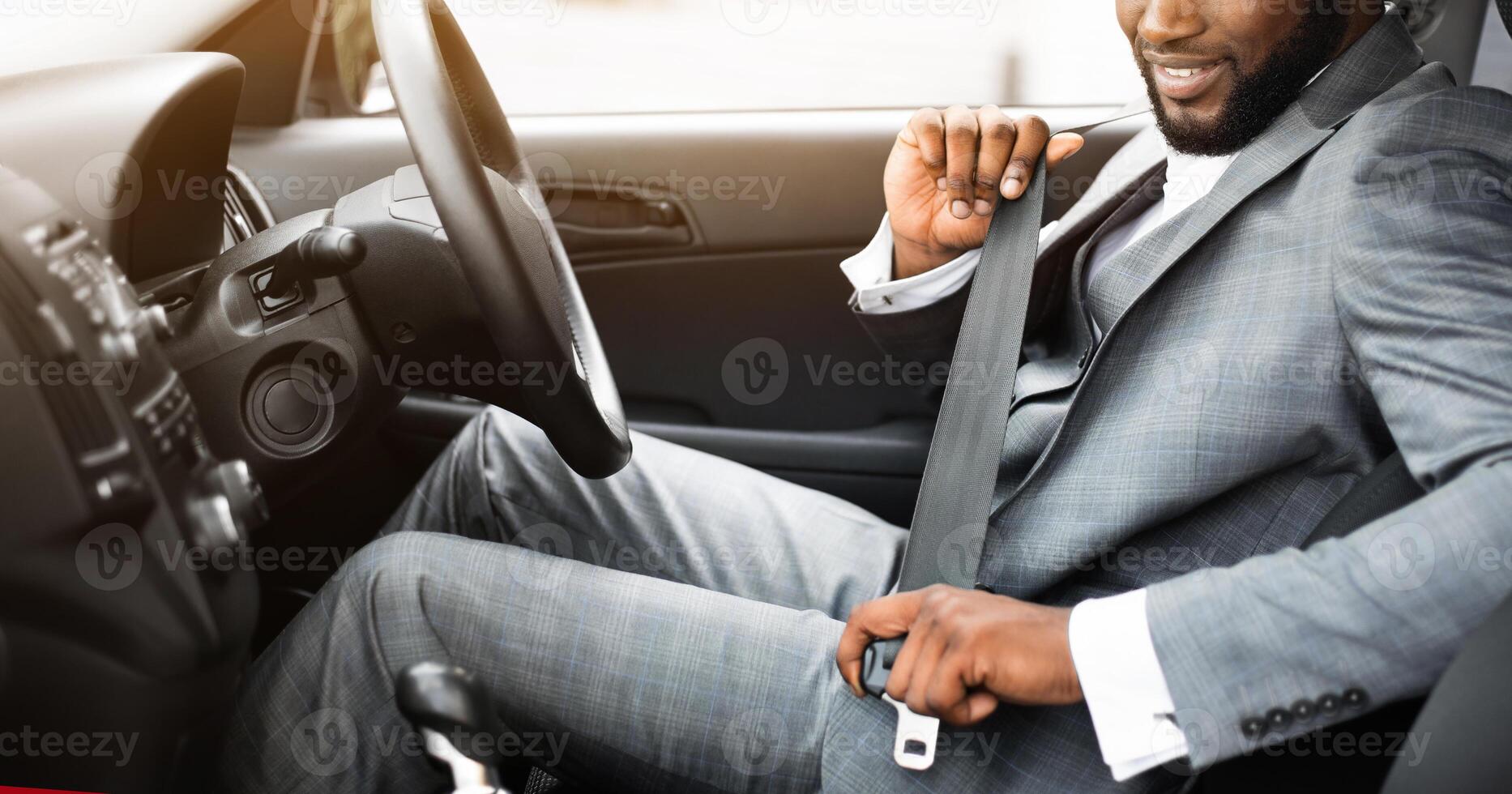 Handsome black businessman fasten seat belt in his car, ready to go to office photo