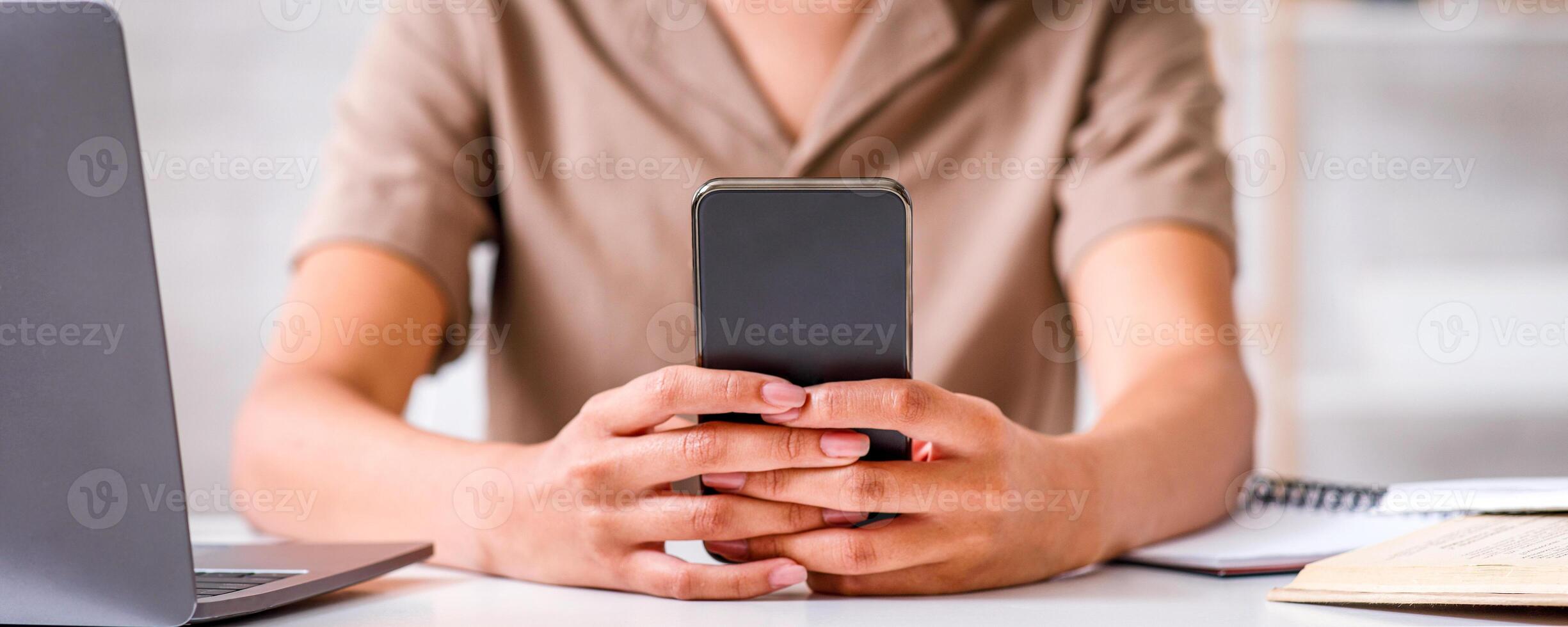 Modern technology for working at home. African american girl typing on smartphone, sits at table with laptop and notepads in living room interior, cropped photo
