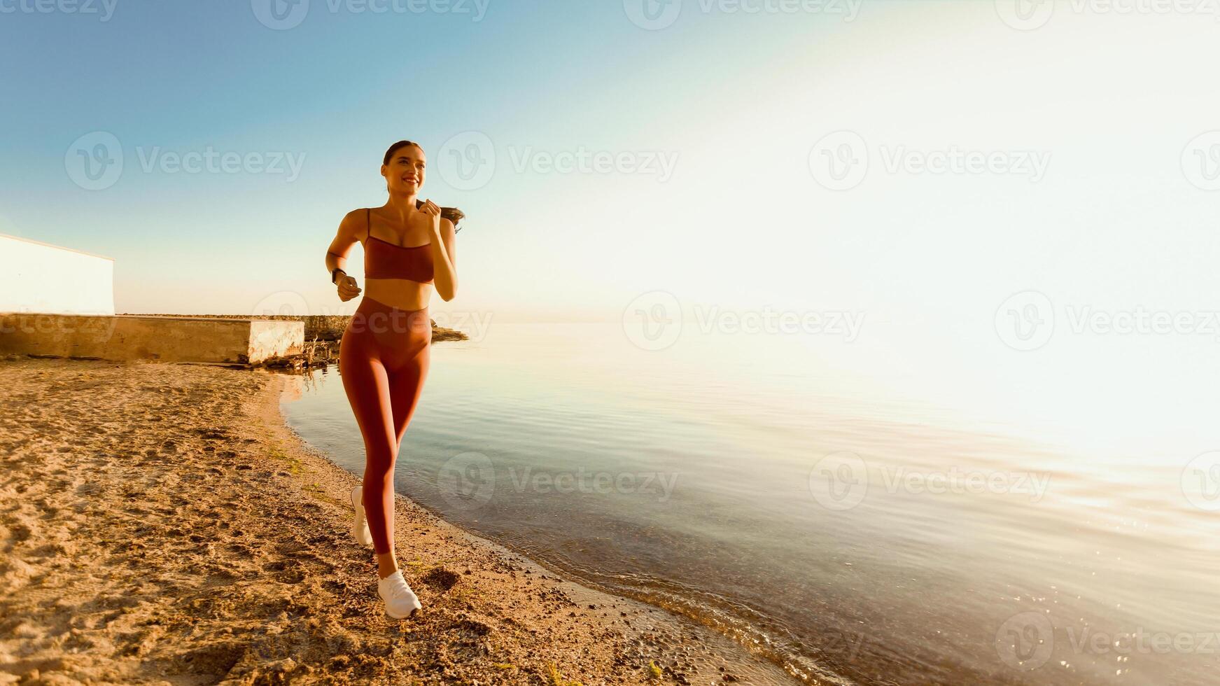 Strength Concept. Smiling sportive lady in bra and leggings running at the sea shore, copy space, banner photo
