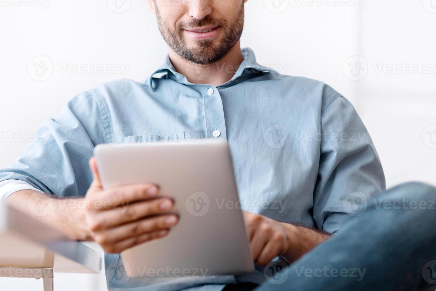 Portrait Of Handsome Young Man Using Digital Tablet During Break In Office, Browsing Internet Or Social Media, Checking New App, photo