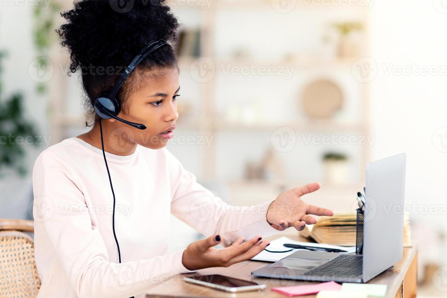 Black Girl Sitting At Laptop Having Call With Teacher During Web Class Sitting At Desk At Home. Online Education. photo