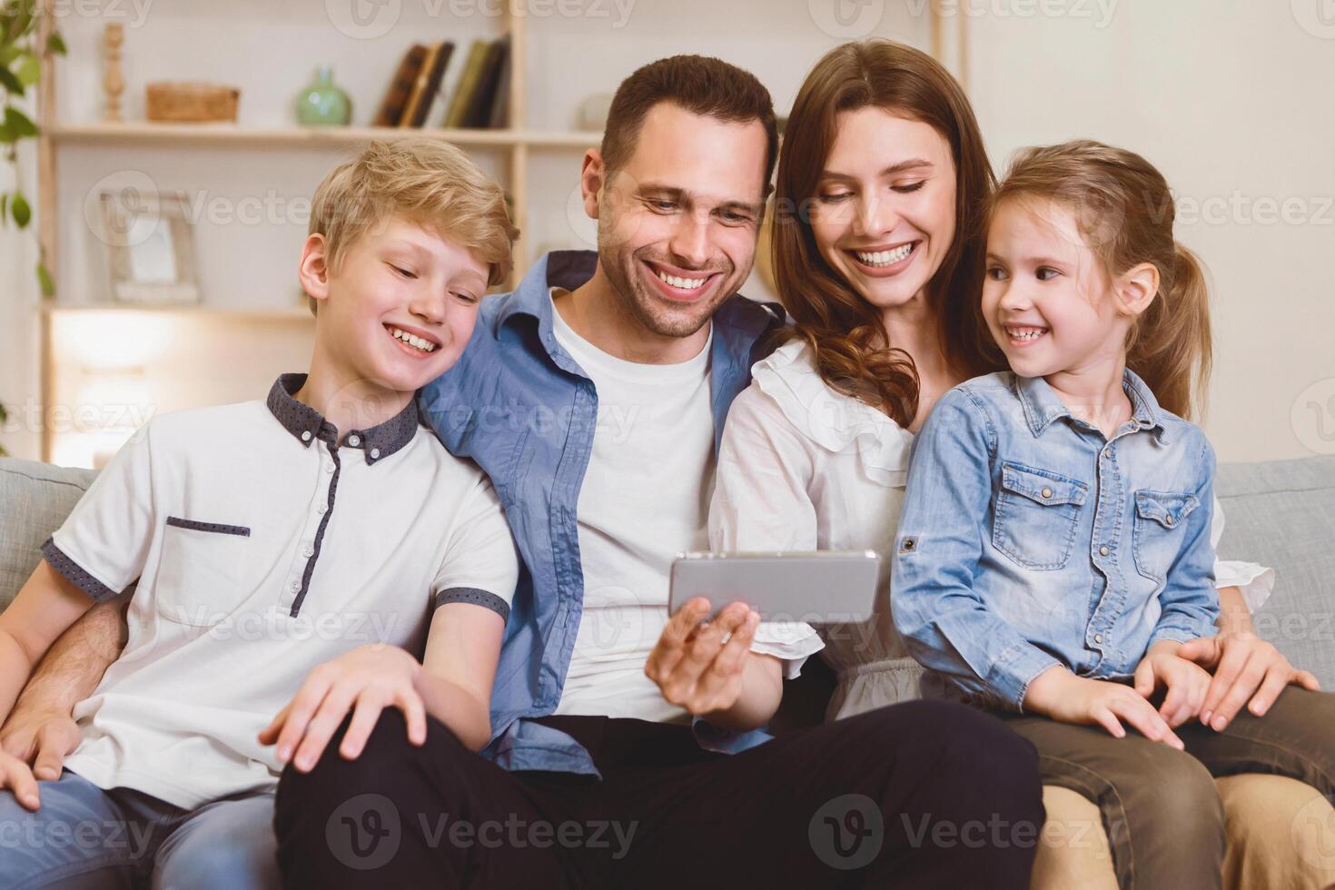 Cheerful Family Using Smartphone Browsing Internet Together Sitting On Couch At Home On Weekend. Mobile App Concept photo