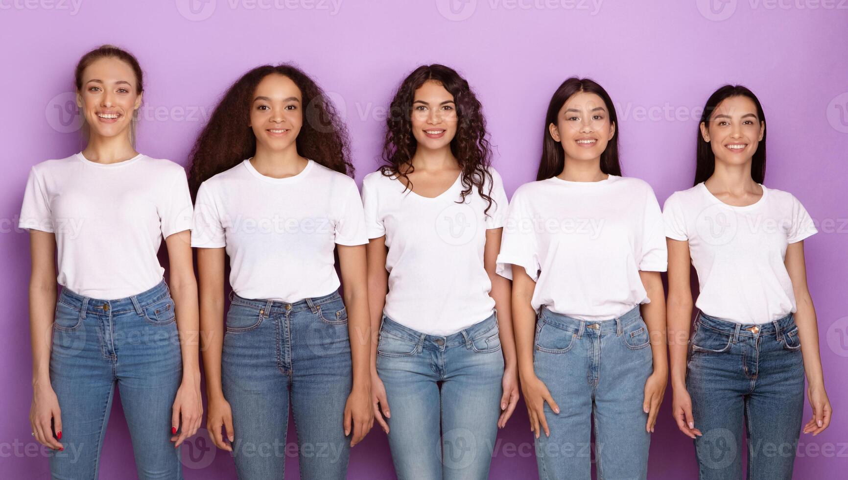 Multicultural Young Ladies Standing Together Looking And Smiling To Camera Over Purple Background. Group Of Millennial Females Posing In Studio. Diversity And Unity Concept. Panorama photo