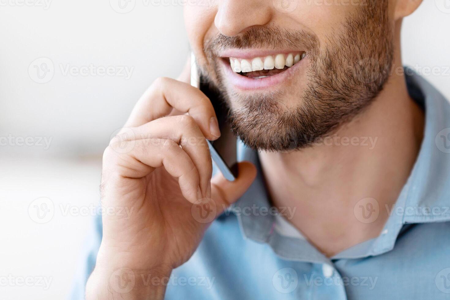 Mobile Call. Handsome Millennial Man Talking On Cellphone Indoors, Smiling Guy With Stubble Enjoying Pleasant Phone Conversation And Communication, Closeup Portrait With Selective Focus And Copy Space photo