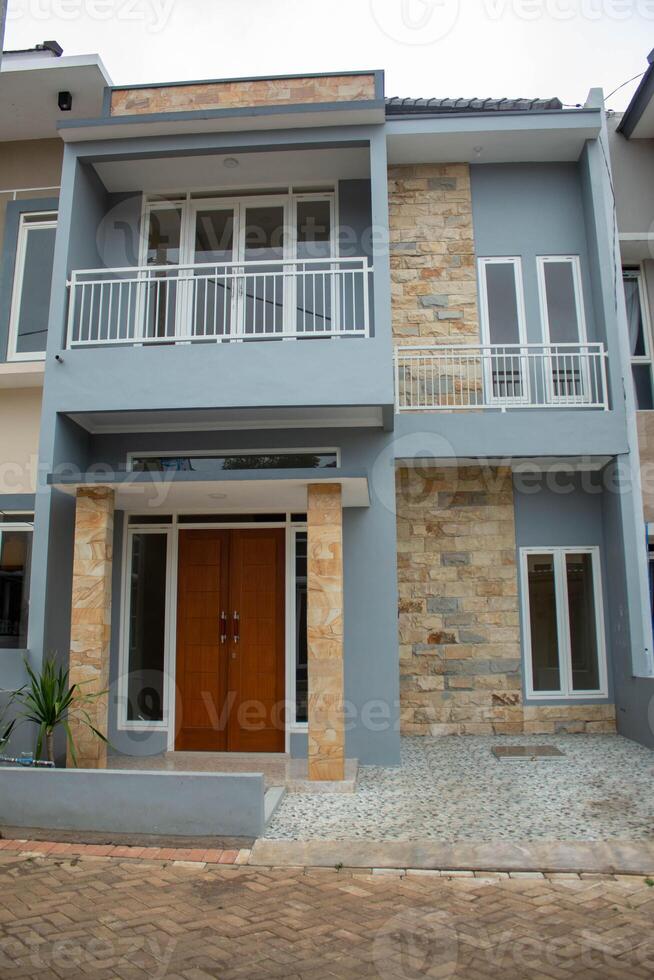 Spacious modern two-story house featuring an elegant wraparound balcony with wrought iron railings under clear blue skies photo