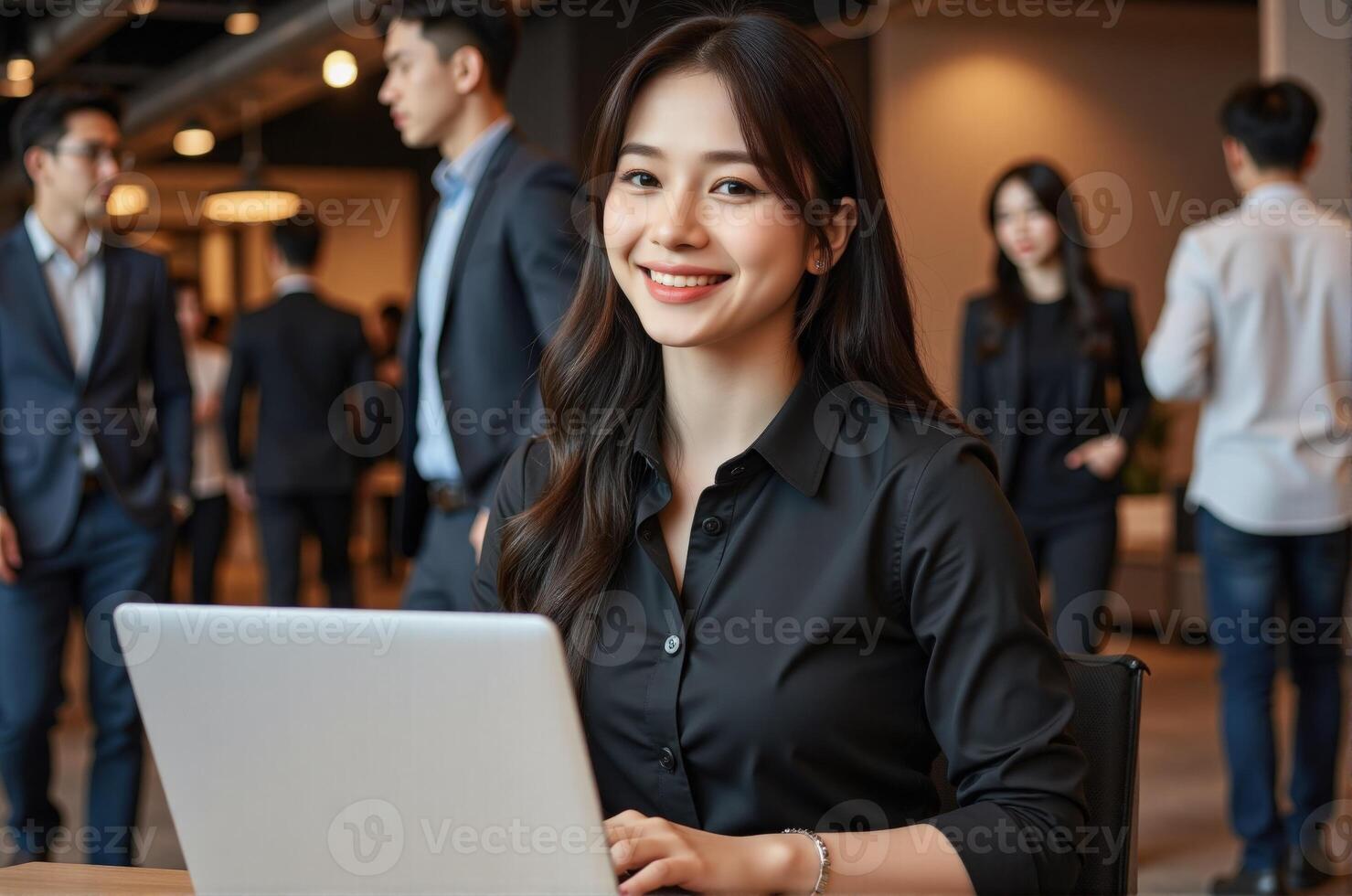 Successful businesswoman sitting with laptop smiling confidently while colleagues work in background modern office setting career woman photo