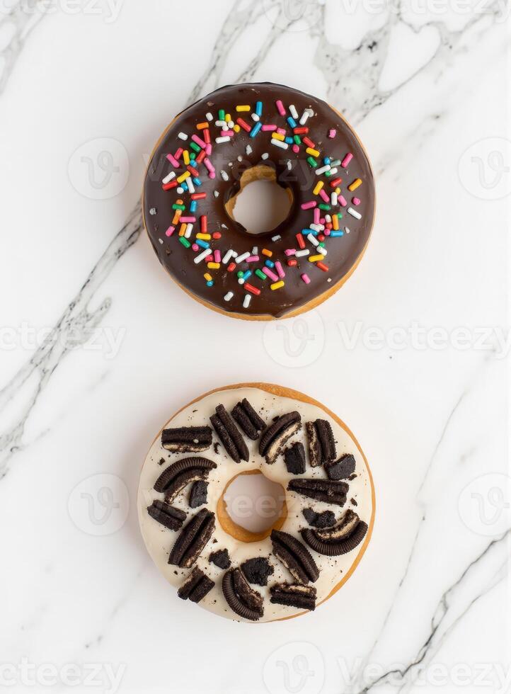 Two donuts enjoyment with chocolate and sprinkles on a marble surface photo
