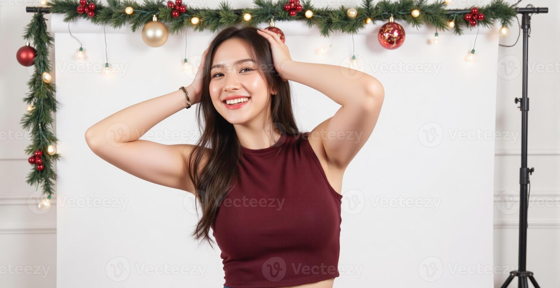 A woman in a maroon top posing in front of a christmas backdrop photo