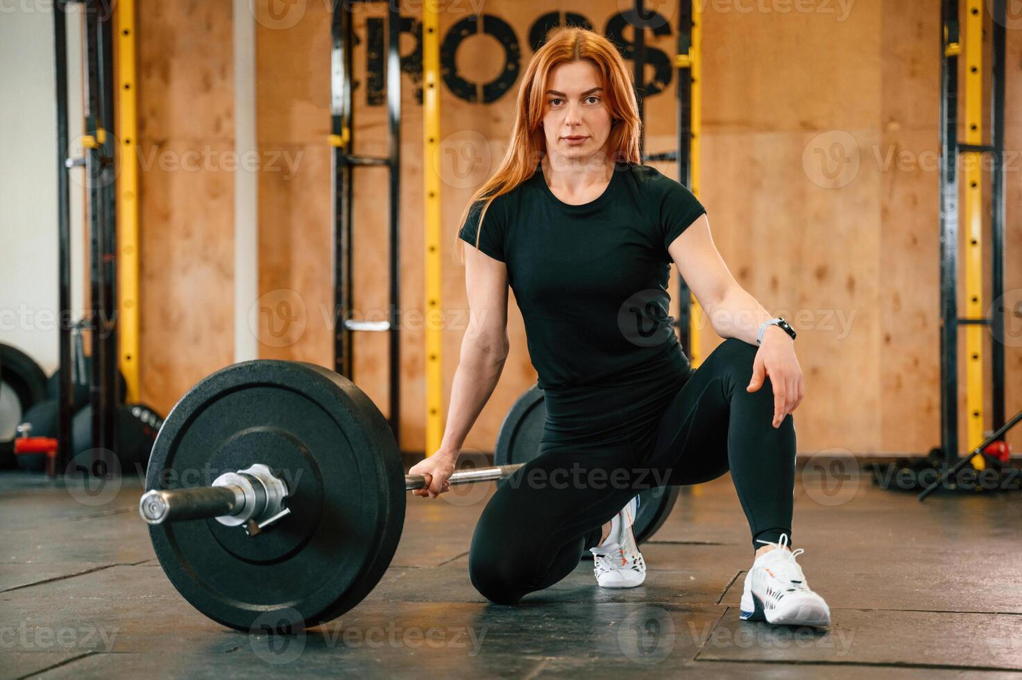 Front view. Sitting, barbell on the floor. .Beautiful ,strong woman is in the gym photo