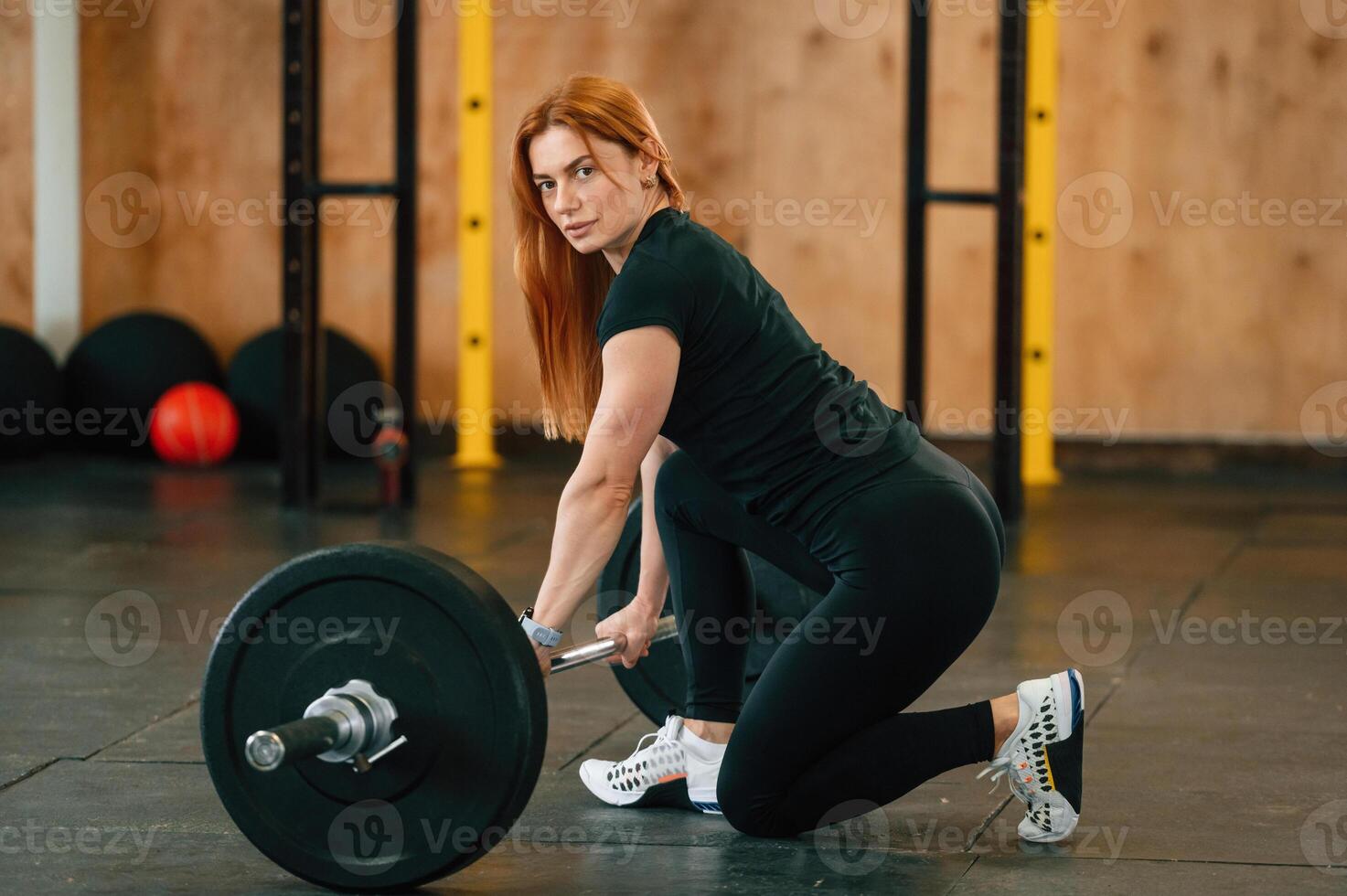 Sitting with barbell, on the floor. Beautiful strong woman is in the gym photo