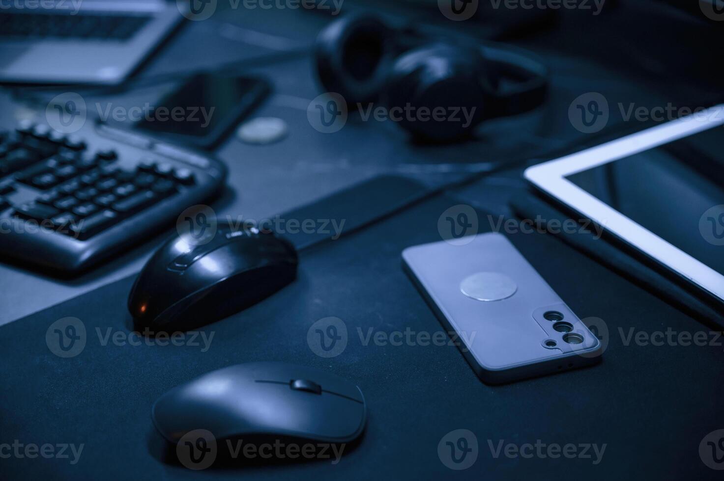 Close up view of table with smartphone, pc mouse, keyboard and headphones photo
