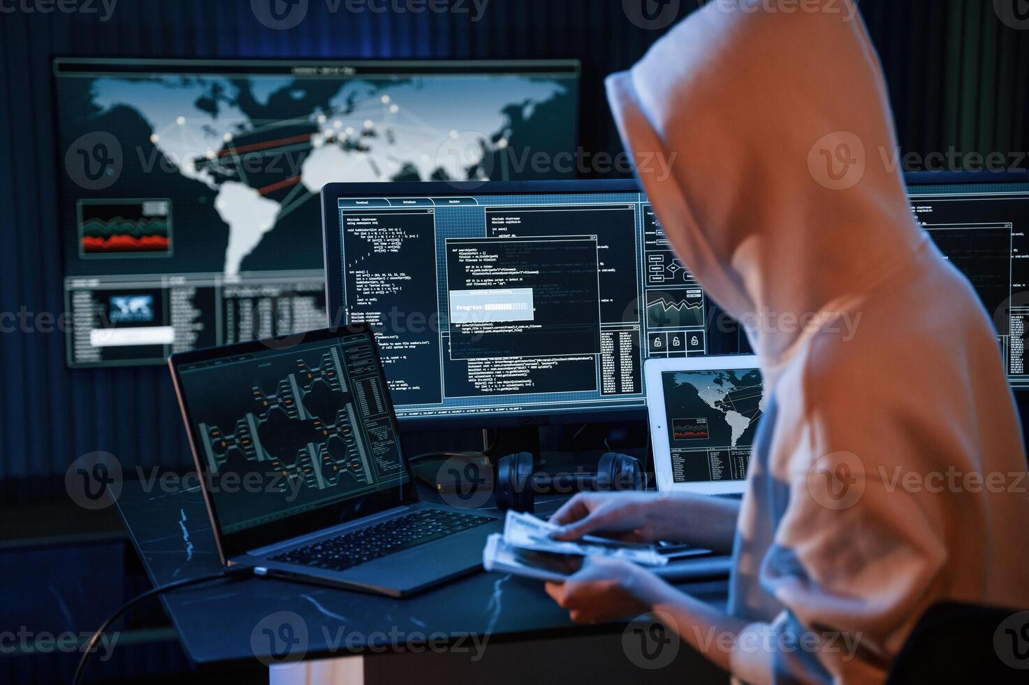 With, currency in hands. Young professional female hacker is indoors by computer with lot of information on displays photo