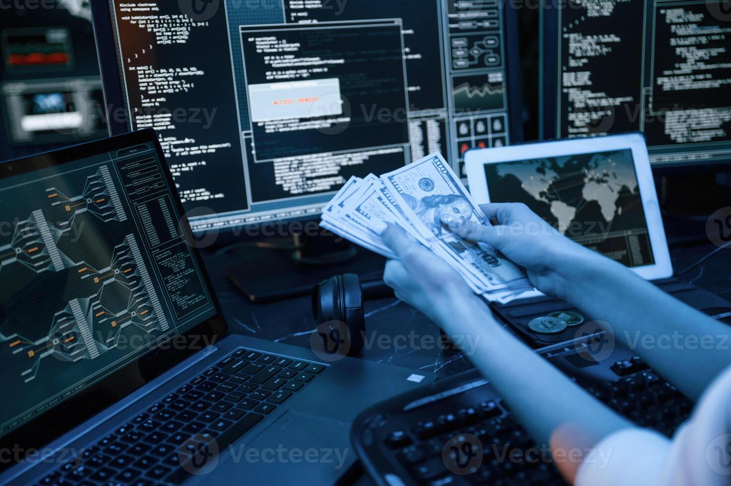 With currency in hands. Young professional female hacker is indoors by computer with lot of information on displays photo