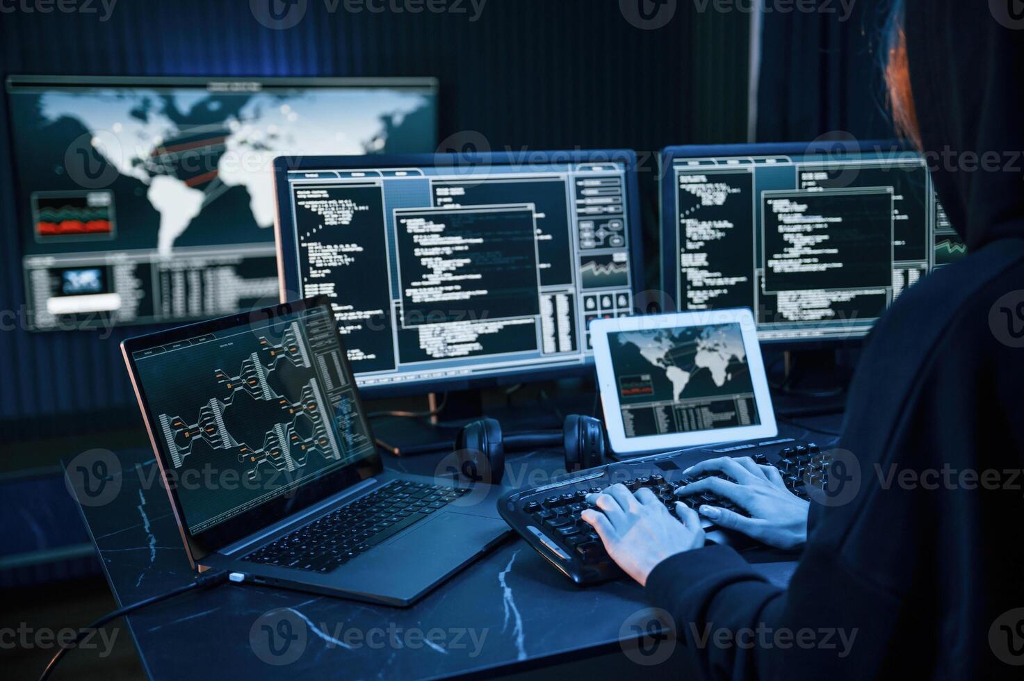 Information on screens. Young professional female hacker is indoors by computer with lot of information on displays,, photo
