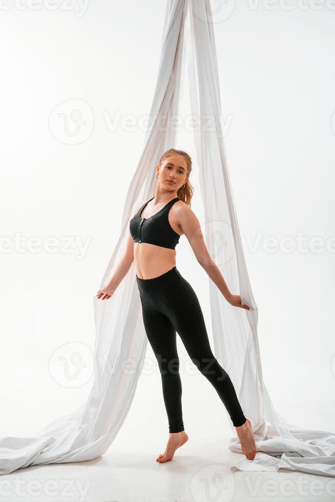 Standing and posing. Young ,beautiful ,woman doing fly yoga against white background photo