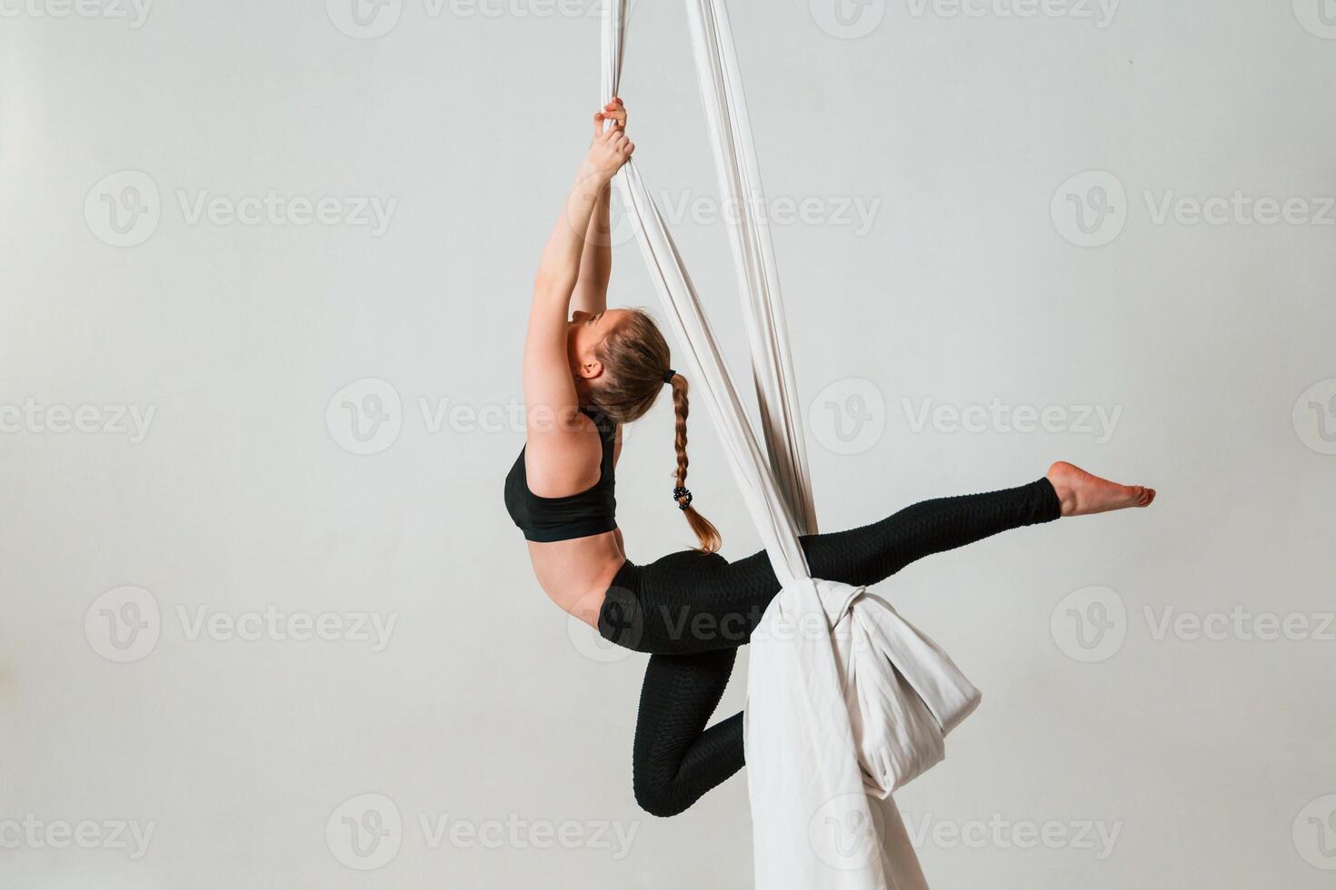In the, midair. Young beautiful woman doing fly yoga against white background photo