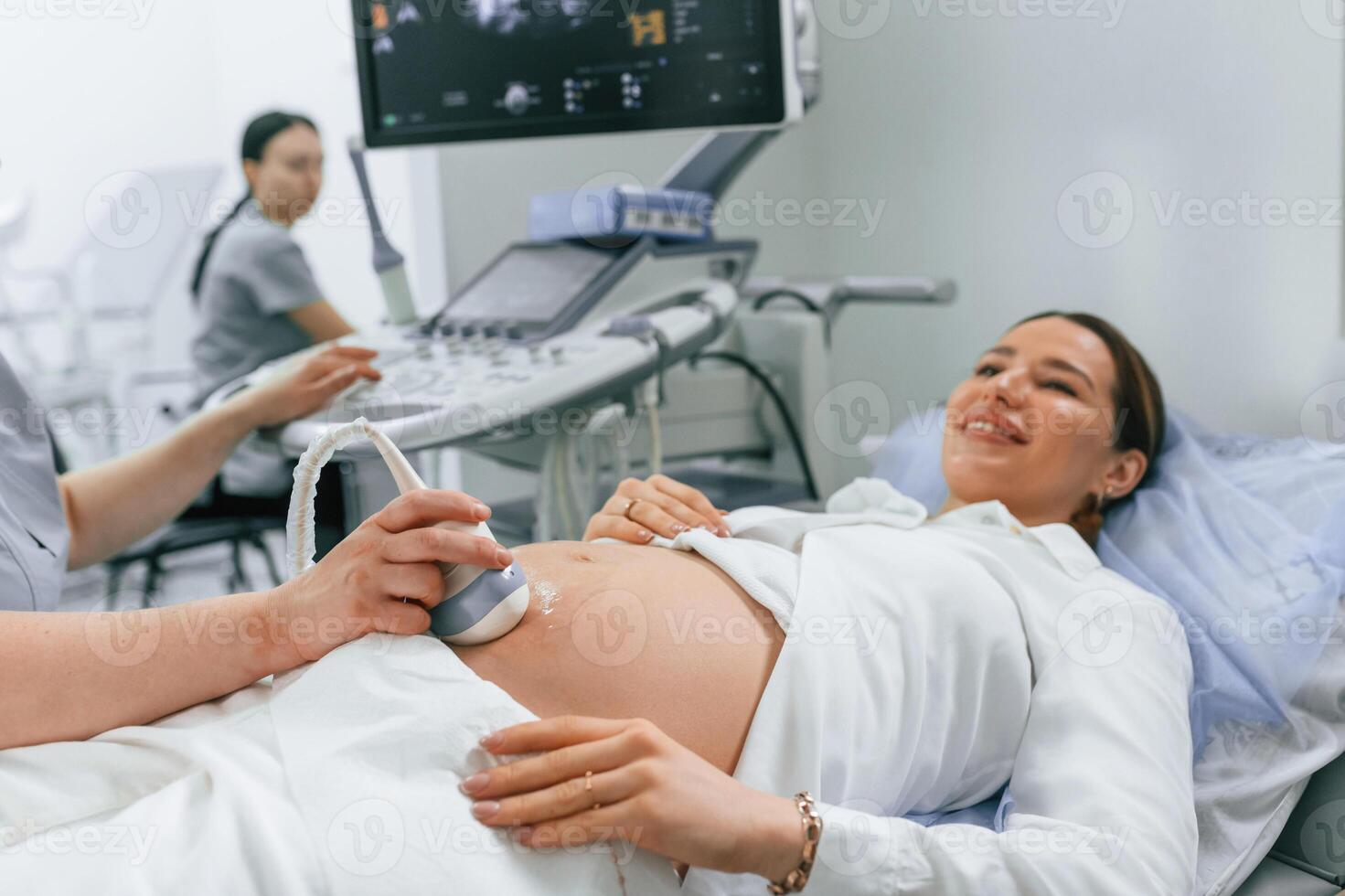 Smiling, medical procedure.. Pregnant woman, is, lying down in the hospital, doctor does ultrasound photo