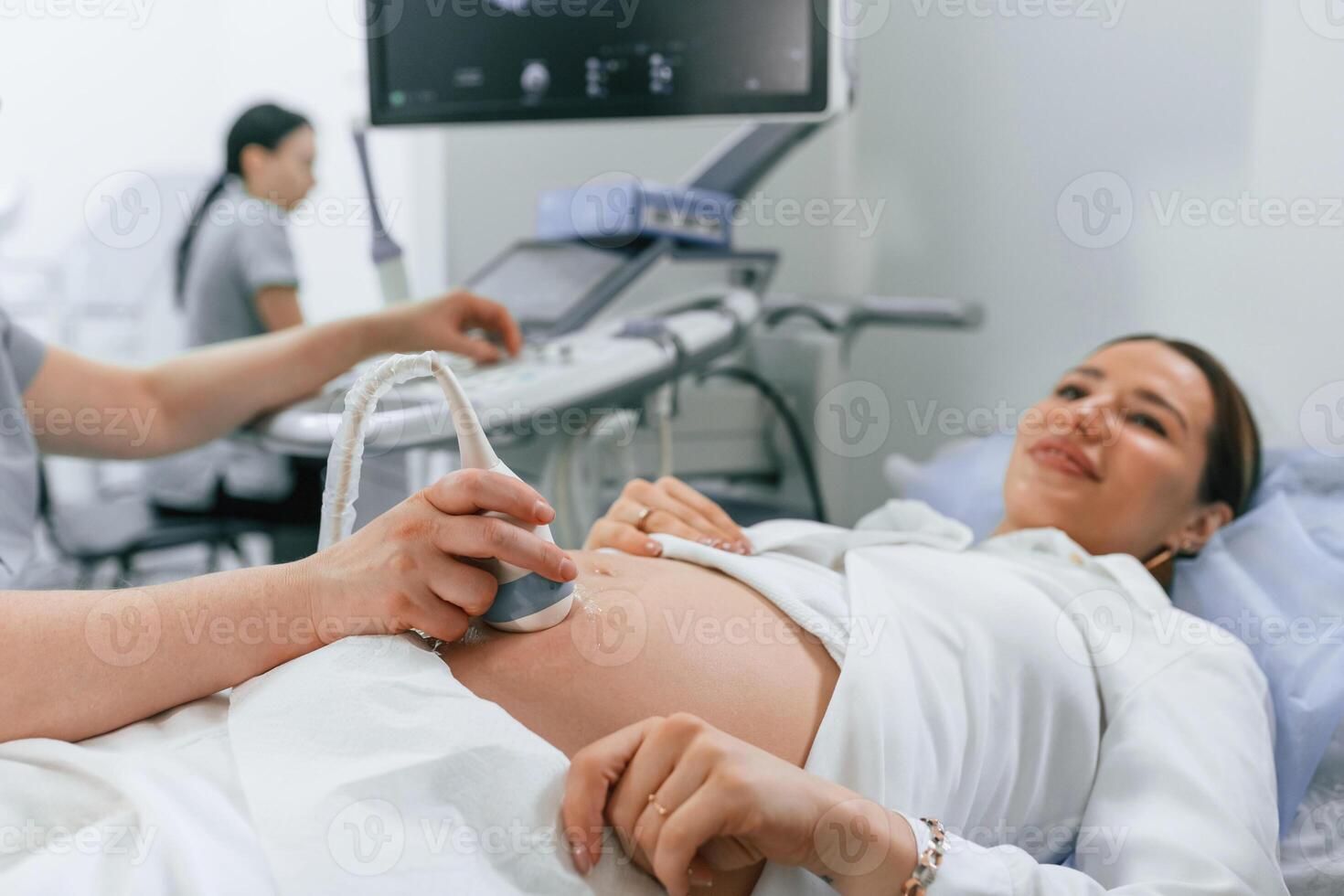 Smiling, medical ,procedure,. Pregnant woman, is lying down in the hospital, doctor does ultrasound photo