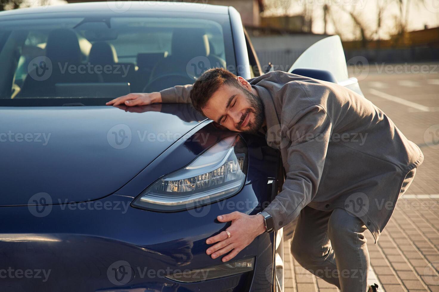 Embracing, the automobile. Man is standing near his electric car outdoors photo
