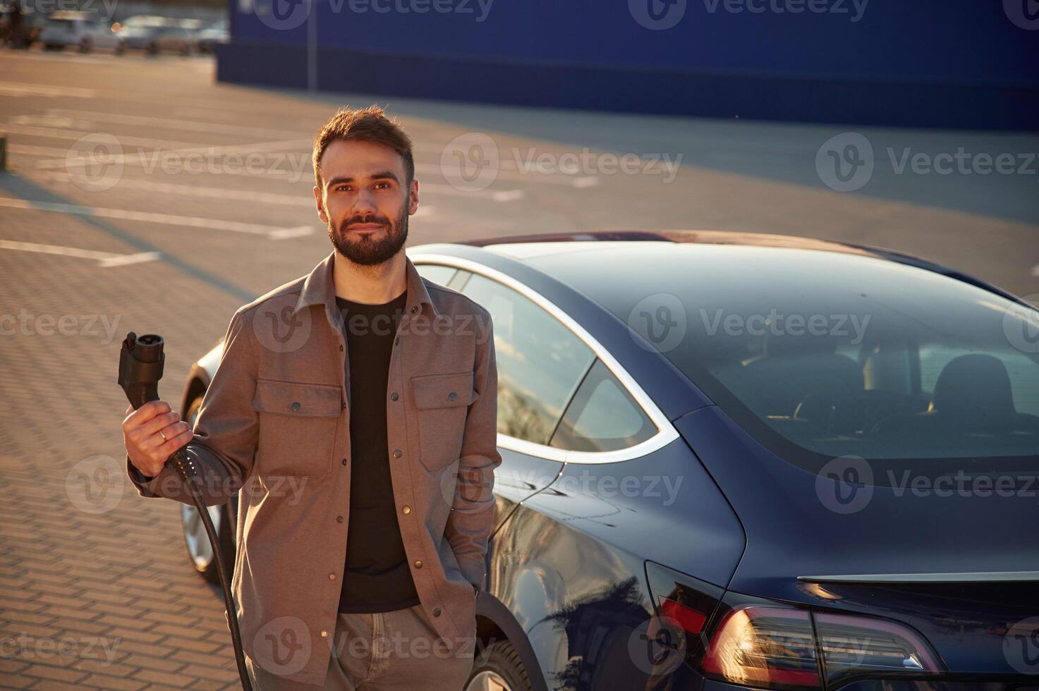 Back ,view ,of the automobile. Man is standing near his electric car outdoors photo