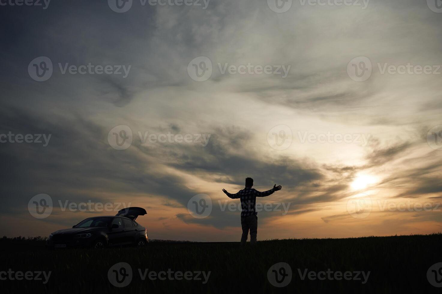 Silhouette of a man that is in ,the, field, at sunset time. Dramatic sky photo
