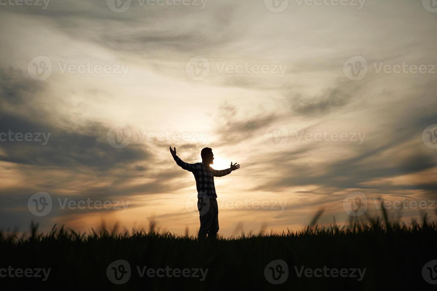 Silhouette of, a man, that is in the field at sunset time. Dramatic sky photo