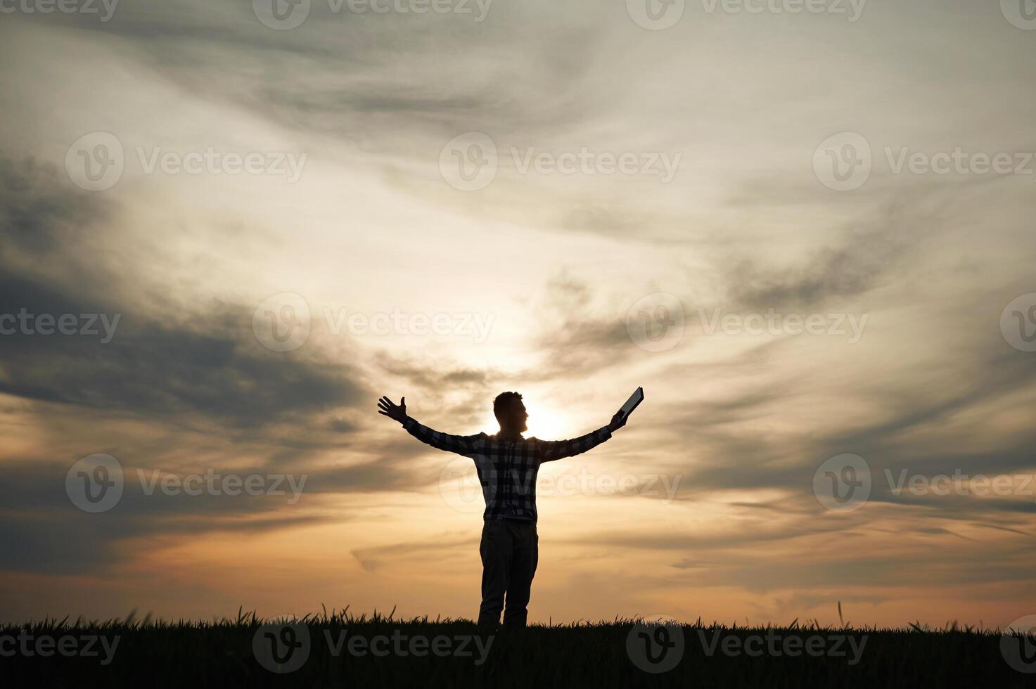 Silhouette of a man ,that is ,in the field at sunset time. Dramatic sky photo