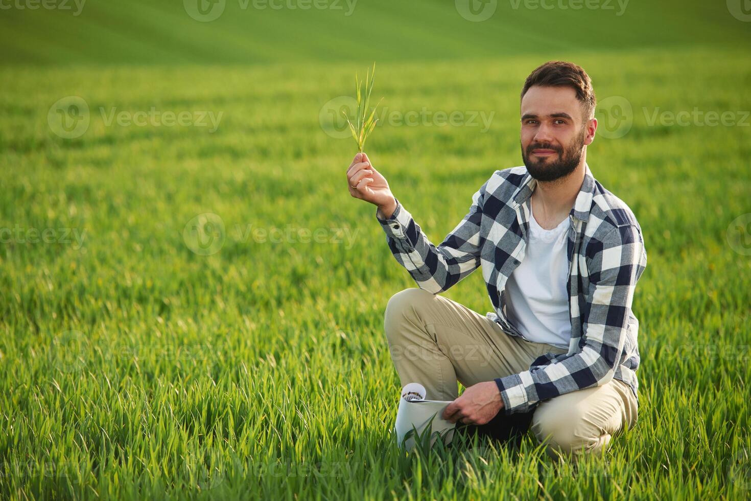 Portrait,, looking at camera, holding wheat. Handsome young man is on agricultural field photo