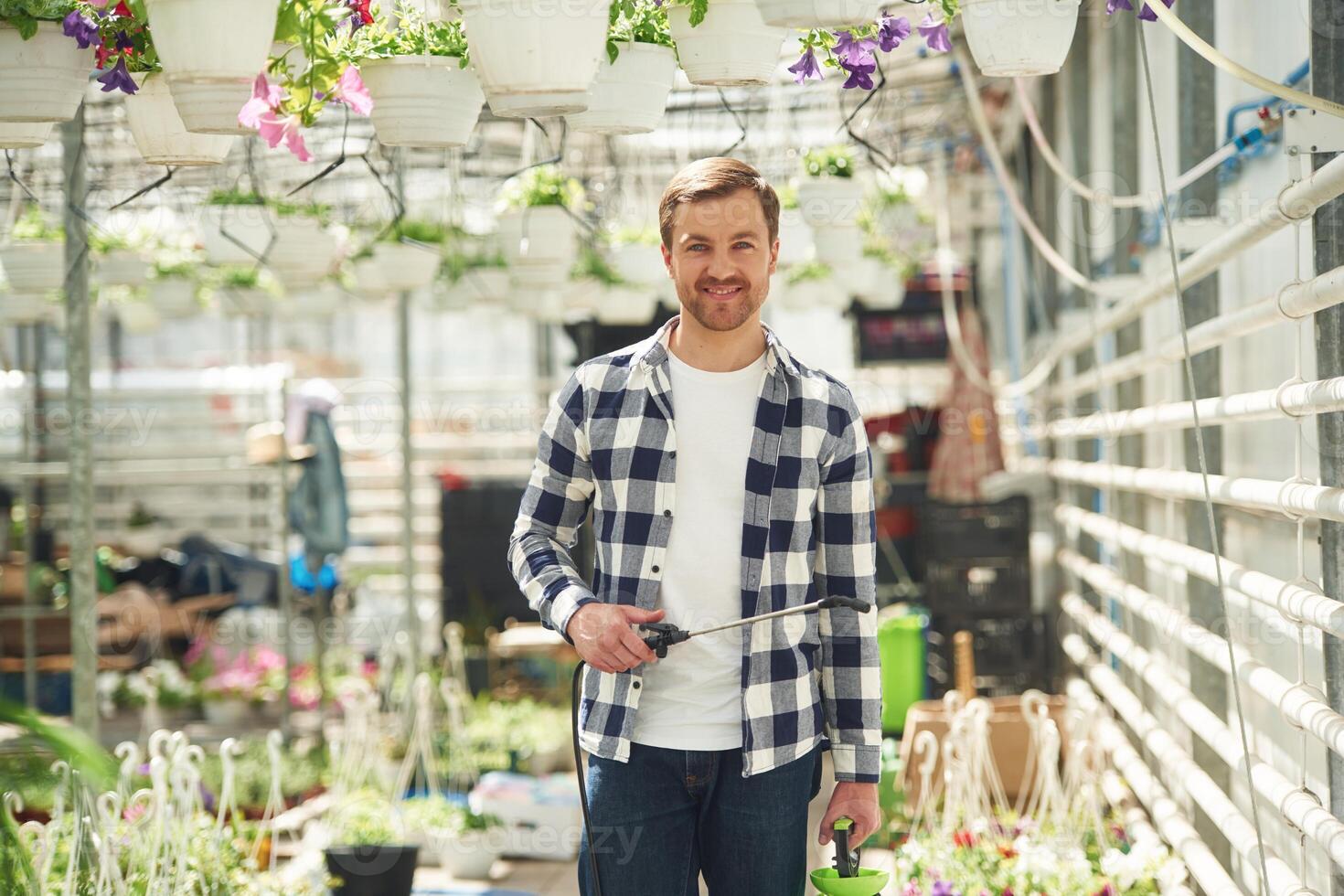 Positive ,florist man is working in garden center. Successful employee is in a bright greenhouse photo