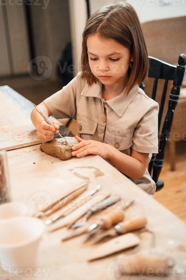 Little girl is learning how to do pottery in the workshop photo