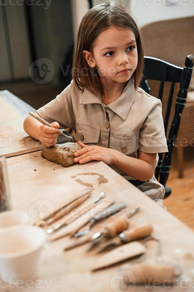 Different tools on the table. Little girl is learning how to do pottery in the workshop photo