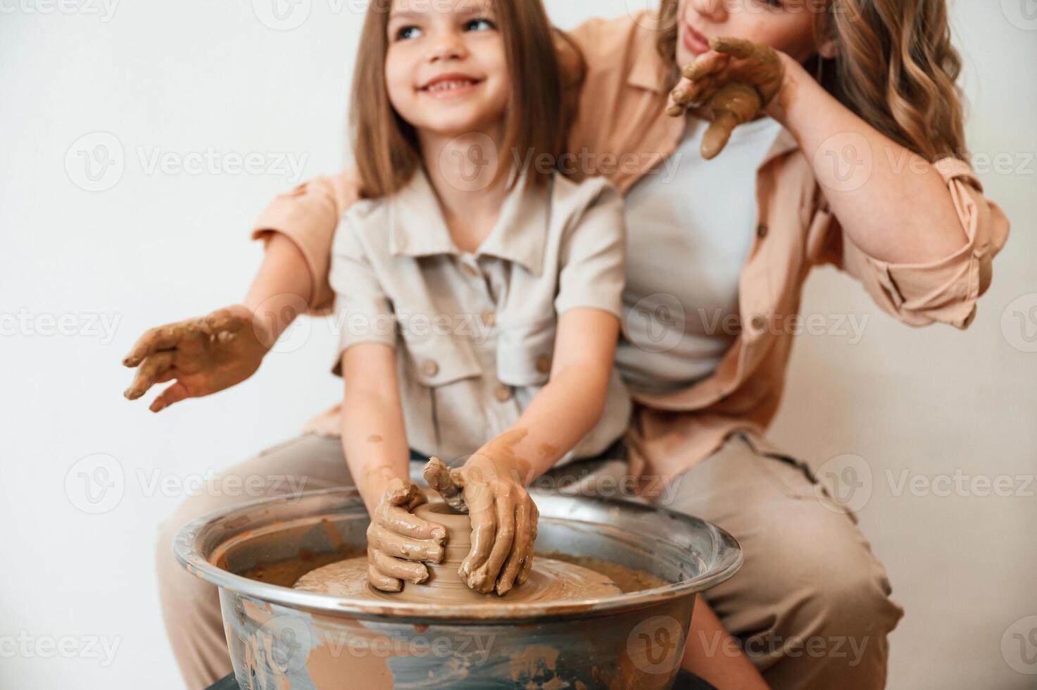 Making the pot out of clay., Mother with little girl doing pottery at home photo