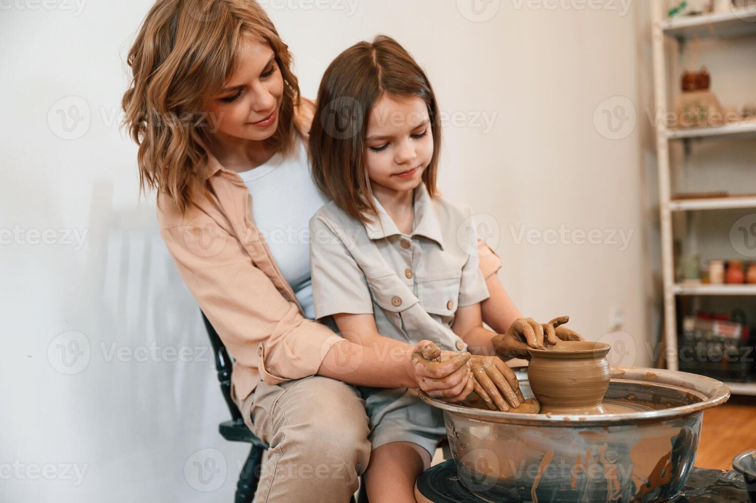 Using clay, to, create the, pot. Mother with little girl learning pottery in the workshop photo