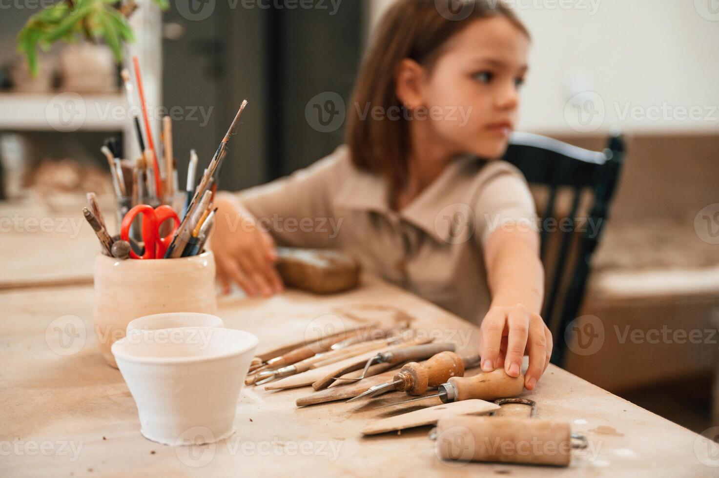 Different tools ,on the, table. Little girl is learning how to do pottery in the workshop photo