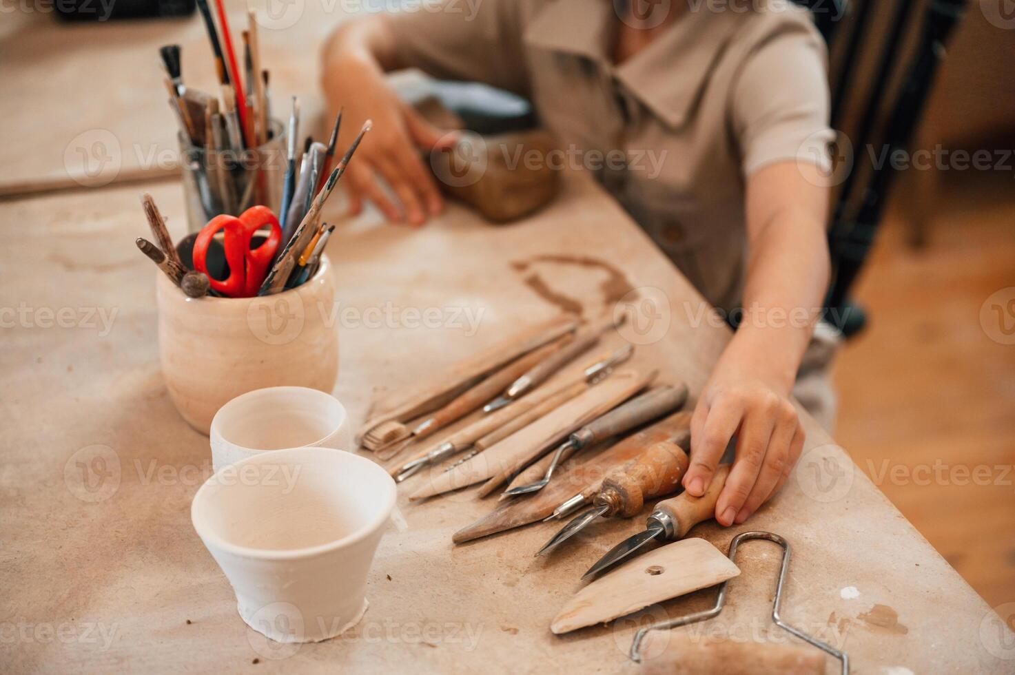 Different ,tools ,on the table. Little girl is learning how to do pottery in the workshop photo