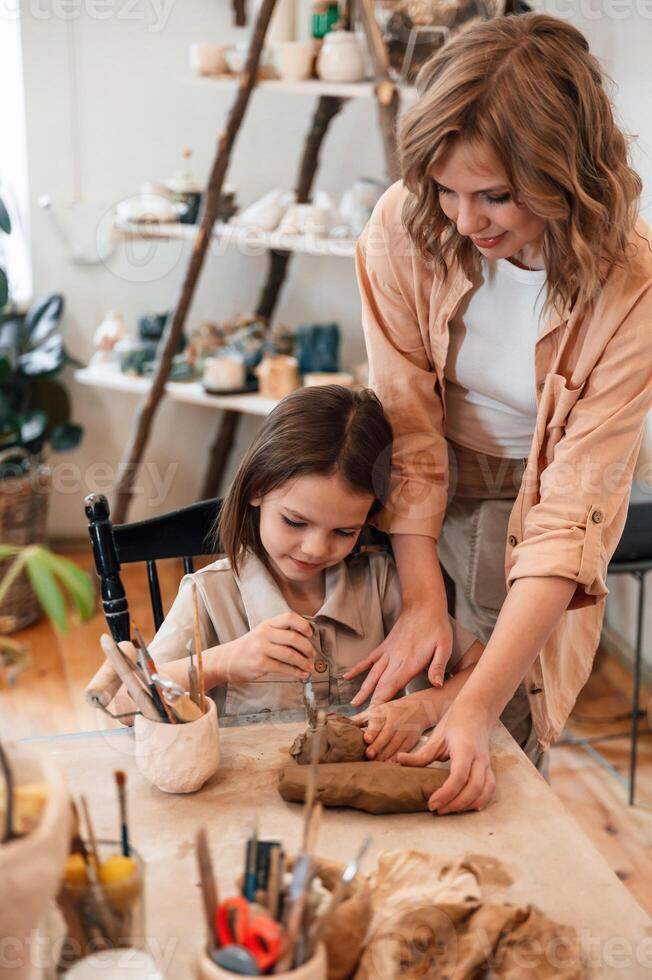 Creating ,the ,shape by using clay. Mother with little girl doing pottery at home photo