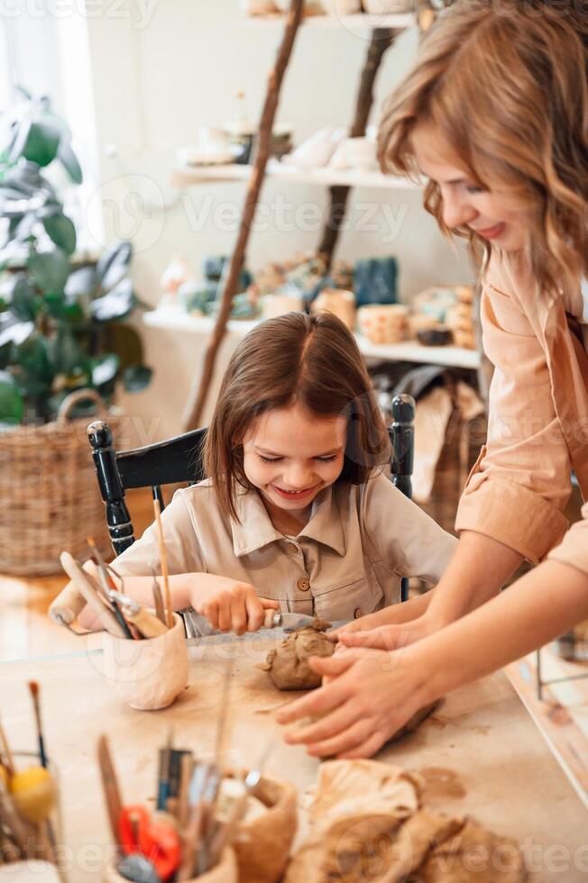 Creating, the ,shape by using clay. Mother with little girl doing pottery at home photo