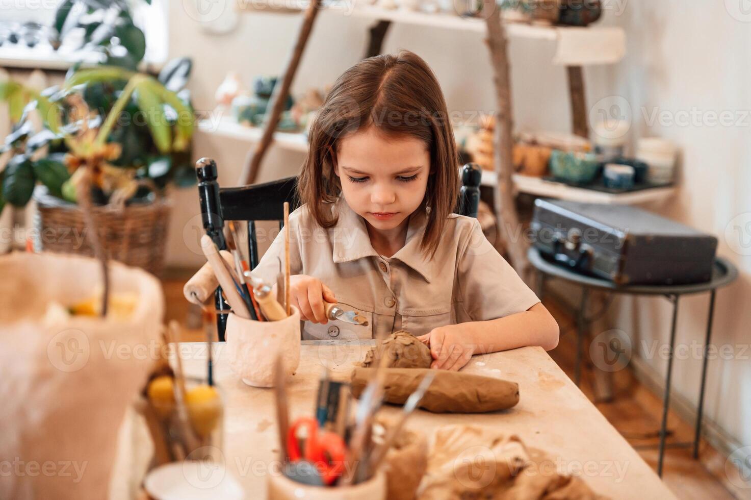 Working ,with ,clay. Little girl is learning how to do pottery in the workshop photo