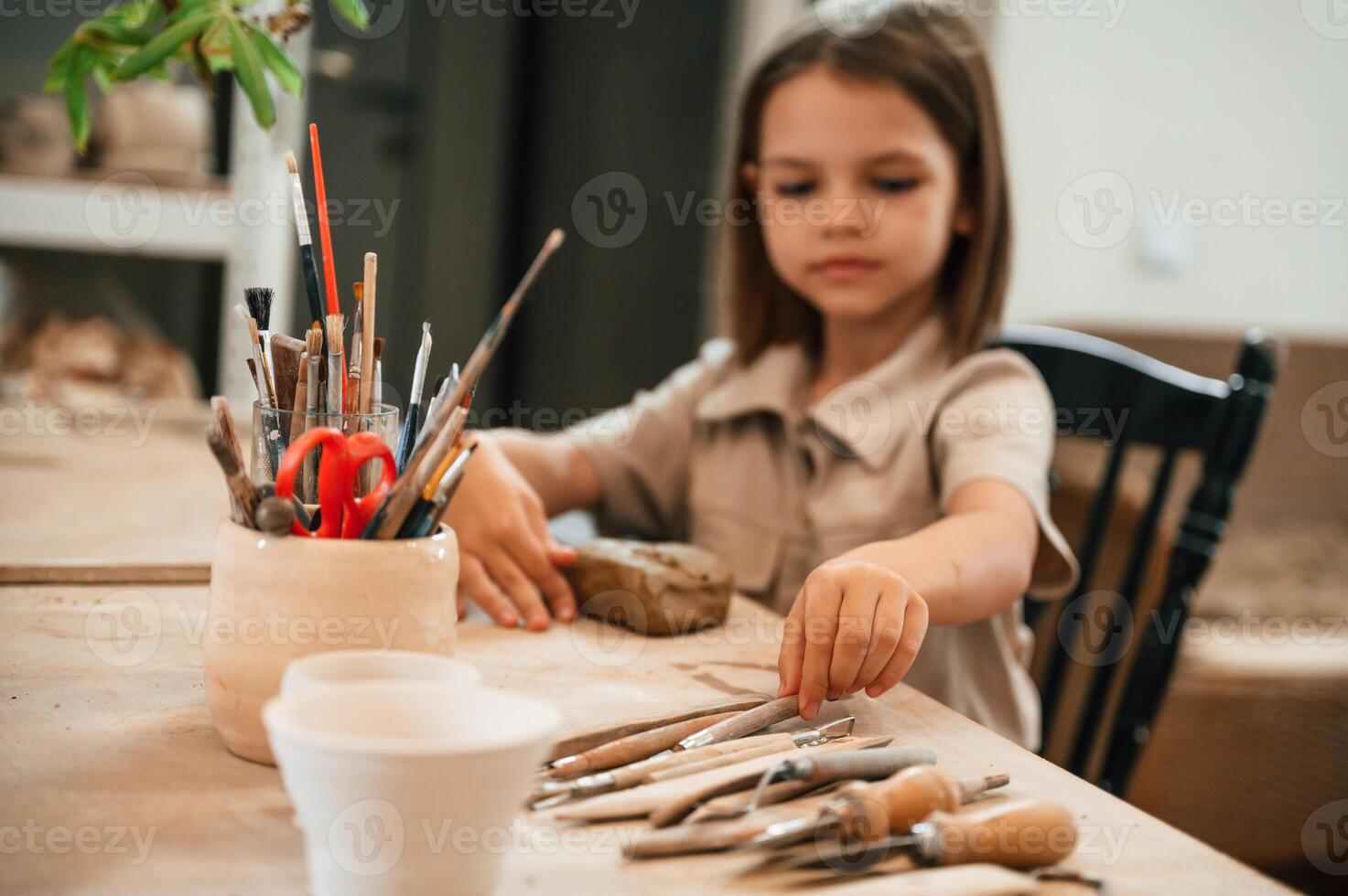 Different ,tools on the table. Little girl is learning how to do pottery in the workshop photo