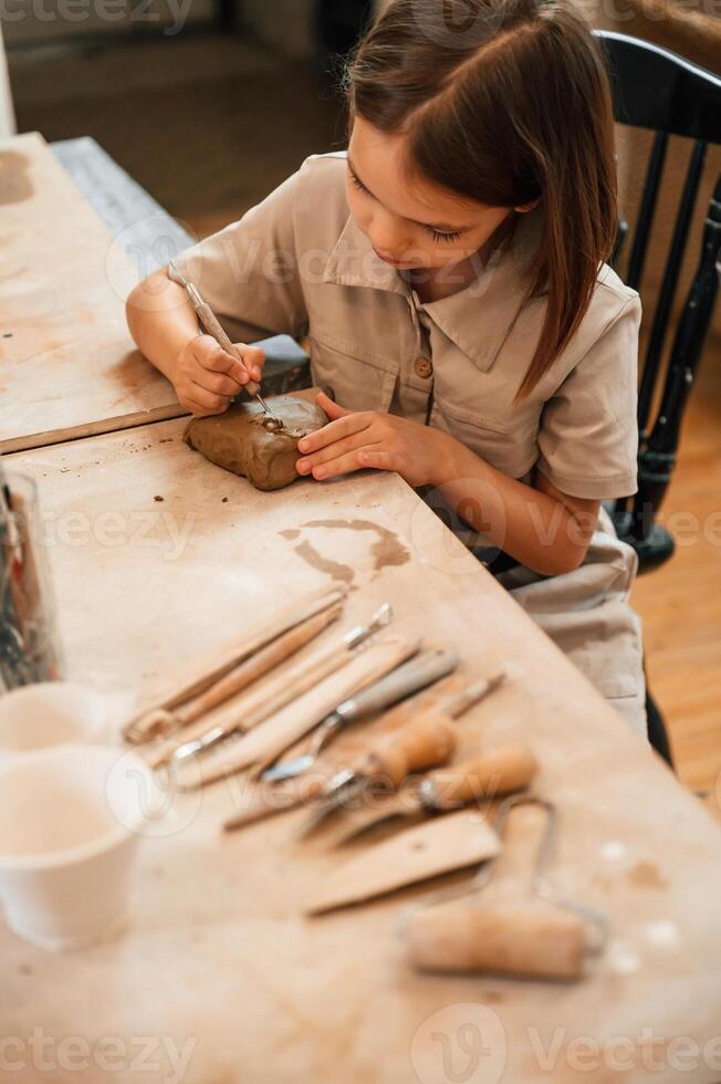 Different, tools on the table. Little girl is learning how to do pottery in the workshop photo