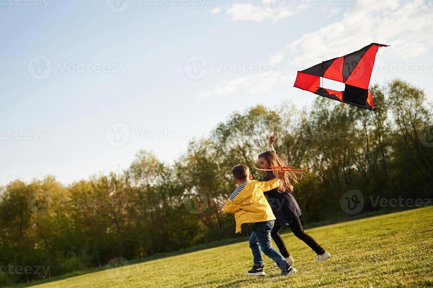 Running together. .Two kids, are playing, with kite on the summer field photo