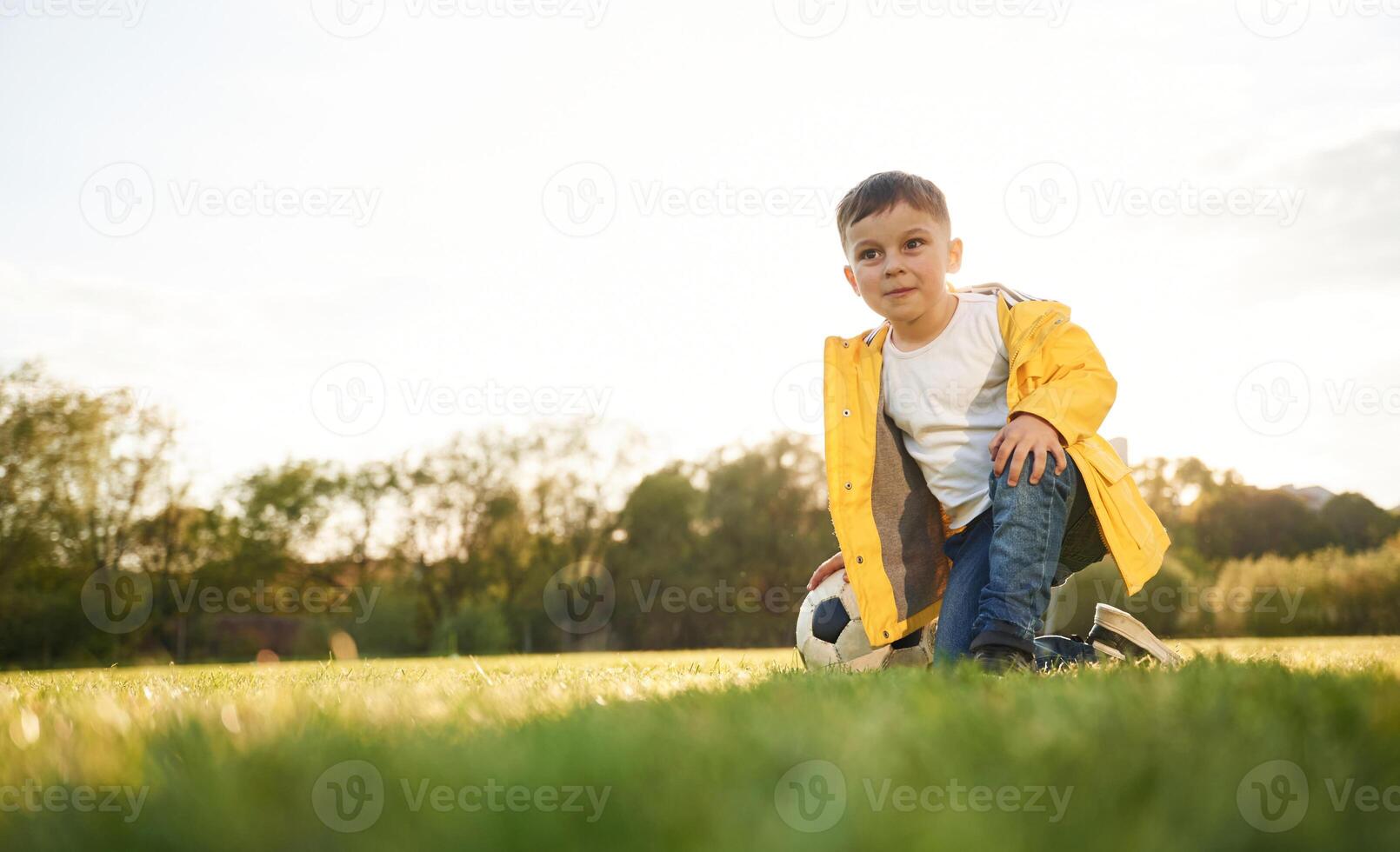 On the ground. Boy is on the summer field ,with soccer ball photo