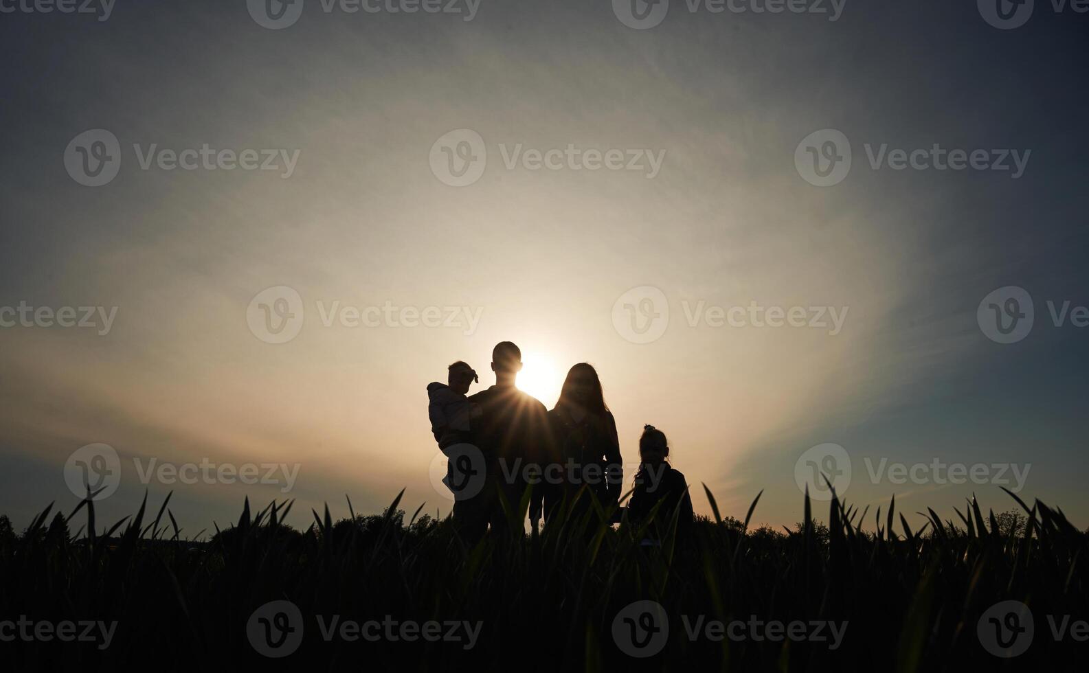 Silhouette, of couple with children, in the field. Amazing sunshine. Dark photo