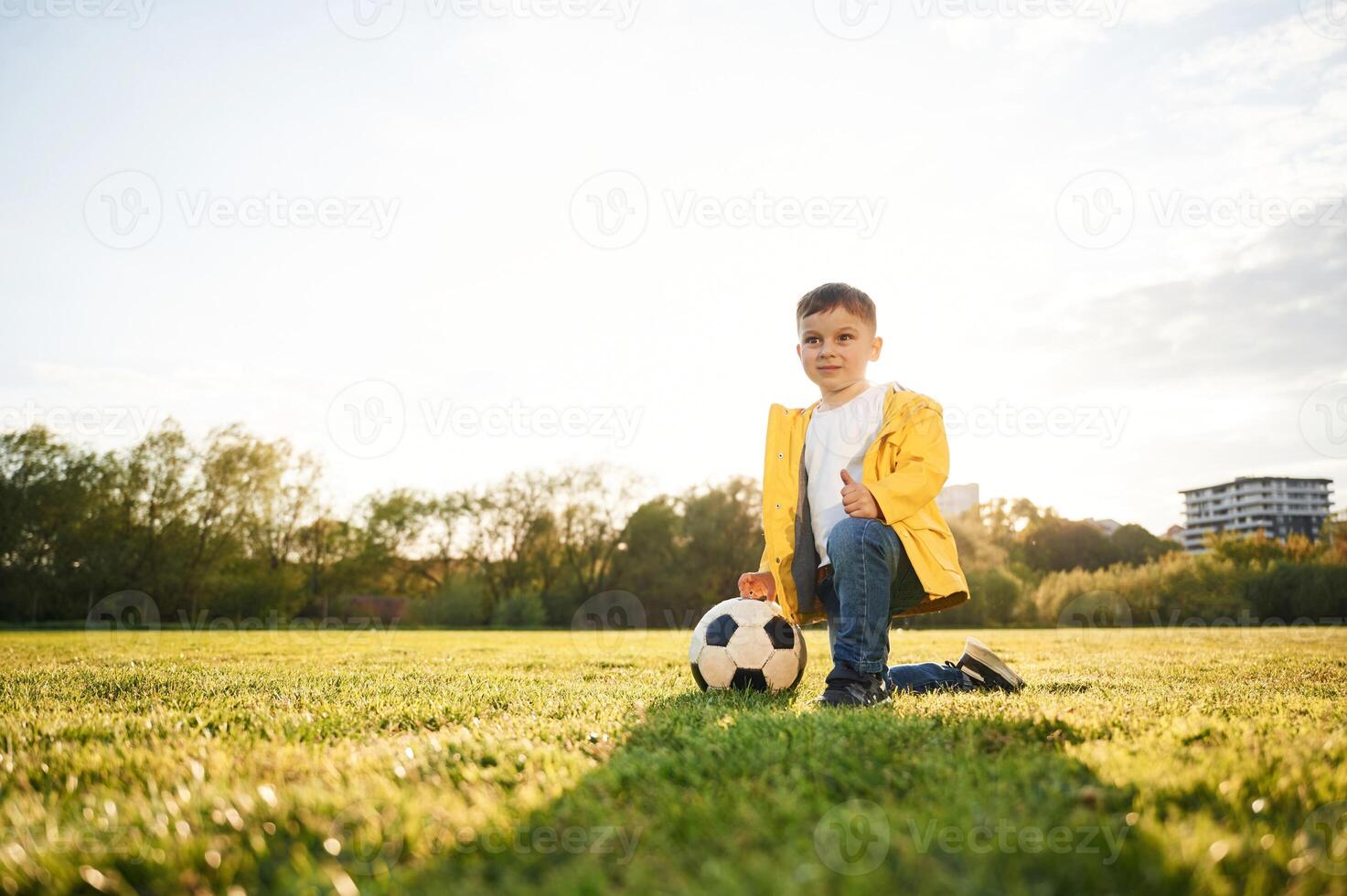 On the ground., Boy is on the summer field with soccer ball photo