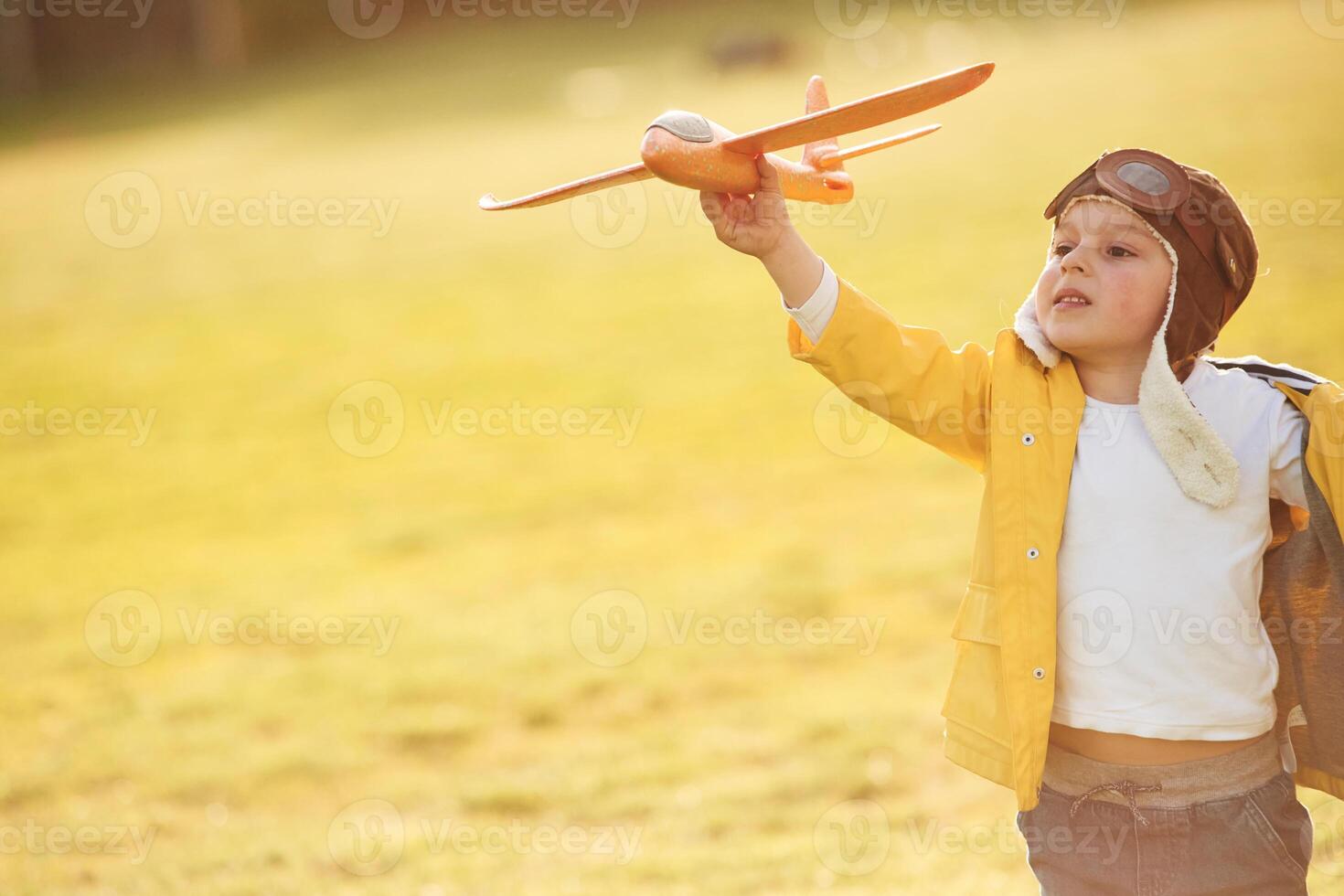 Retro style aviator, glasses. Little boy is playing with toy plane on the summer field photo