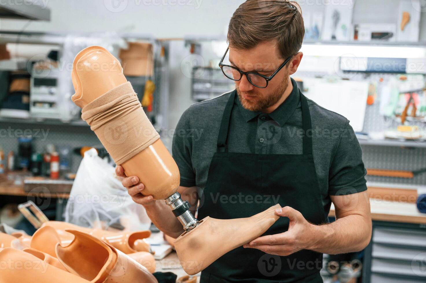 Leg prosthesis in hands. Technician working indoors, photo