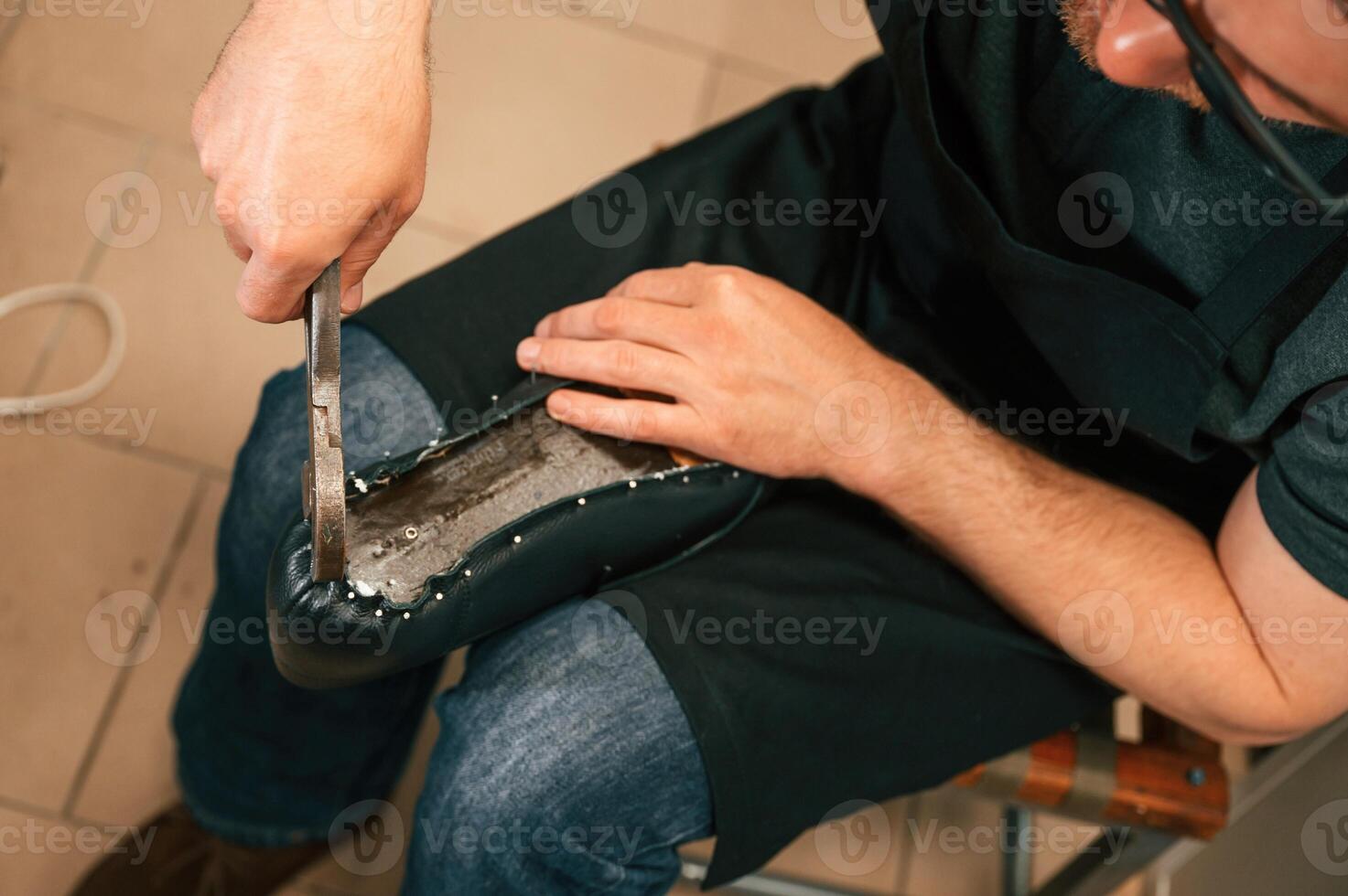 Working with ,nails on the shoe. Close up view of man that is sitting photo