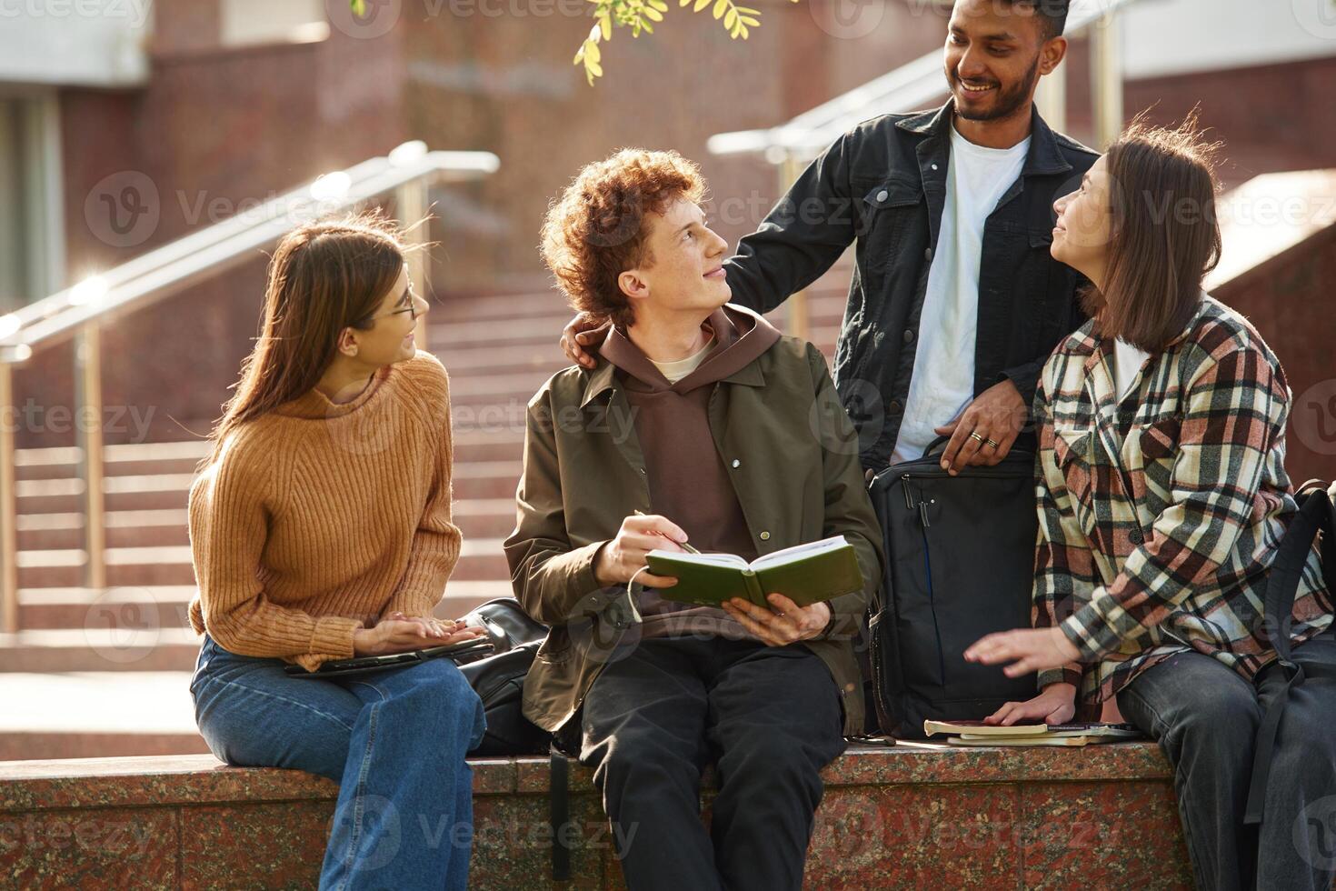 Hanging out after lessons. Four, young s,tudents in casual clothes are together outdoors photo